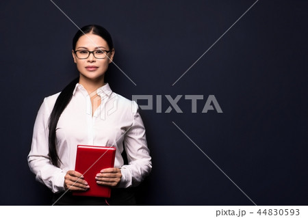 Smiling business woman holding red notebook Smiling business woman holding red notebook 44830593