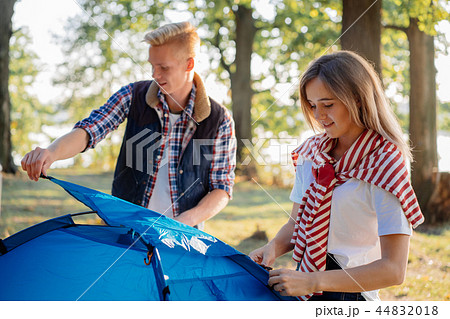Young couple pitching a tent together on hike at the lake Young couple pitching a tent together on hike at the lake 44832018