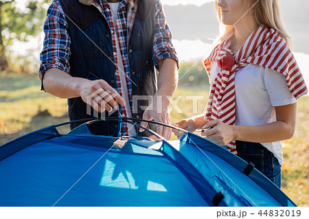 Young couple pitching a tent together on hike at the lake Young couple pitching a tent together on hike at the lake 44832019