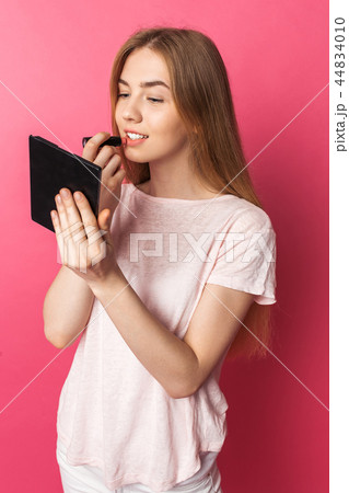 A young girl paints lips with lipstick A young girl paints lips with lipstick 44834010