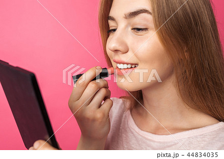 A young girl paints lips with lipstick A young girl paints lips with lipstick 44834035
