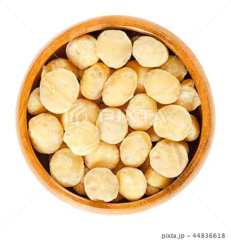 Roasted macadamia nuts in wooden bowl over white Roasted macadamia nuts in wooden bowl over white 44836618