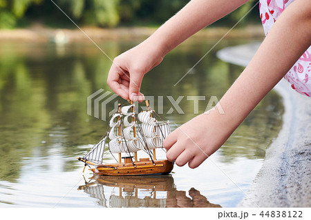 girl playing with a toy sailing ship by the river girl playing with a toy sailing ship by the river 44838122