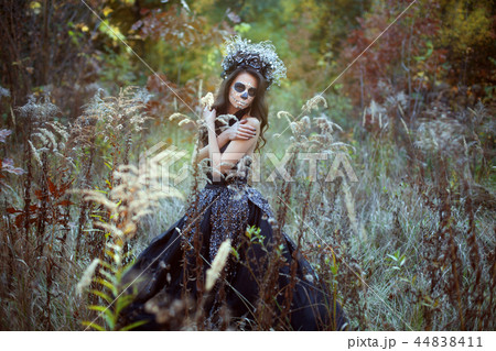 Woman with make-up for Halloween in a fairy forest. Woman with make-up for Halloween in a fairy forest. 44838411