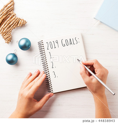 Woman's hand writing 2019 Goals in notebook. 44838943