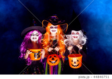 Three Beautiful girl in a witch costume on a dark background in smoke scaring and making faces 44840751