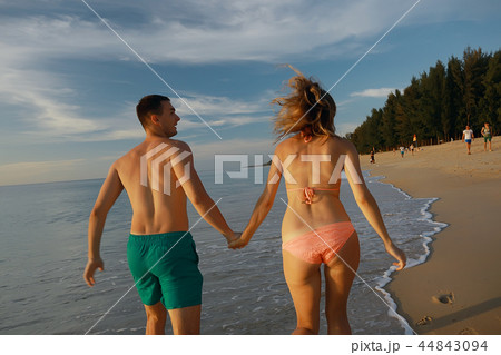 lovers run along the beach / guy and girl run along the summer sea beach, rest on the sea honeymoon lovers run along the beach / guy and girl run along the summer sea beach, rest on the sea honeymoon 44843094