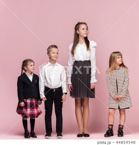 Cute stylish children on pink studio background. The beautiful teen girls and boy standing together Cute stylish children on pink studio background. The beautiful teen girls and boy standing together 44854540