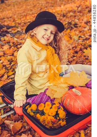 Little beautiful blond girl with big pumpkin in autumn background 44856280