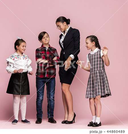 Cute stylish children on pink studio background. The beautiful teen girls and boy standing together Cute stylish children on pink studio background. The beautiful teen girls and boy standing together 44860489