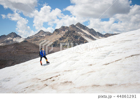 Traveler in a cap and sunglasses with a backpack on his shoulders in the snowy mountains on the Traveler in a cap and sunglasses with a backpack on his shoulders in the snowy mountains on the 44861291