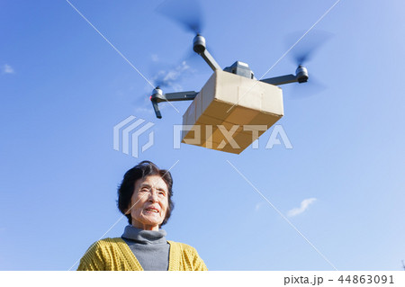 ドローンで荷物を受け取るシニア女性 44863091