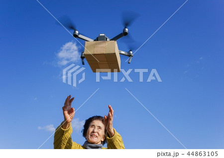 ドローンで荷物を受け取るシニア女性 44863105
