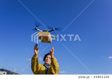 ドローンで荷物を受け取るシニア女性 44863108