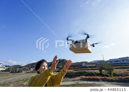 ドローンで荷物を受け取るシニア女性 44863113