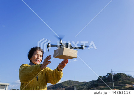 ドローンで荷物を受け取るシニア女性 44863118