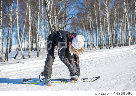 Young adult woman snowboarder standing on board Young adult woman snowboarder standing on board 44869990