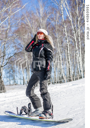 Young adult woman snowboarder standing on board 44869991