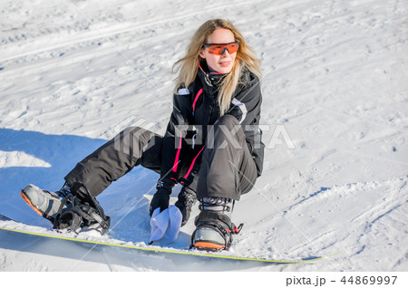 Young adult woman snowboarder standing on board Young adult woman snowboarder standing on board 44869997
