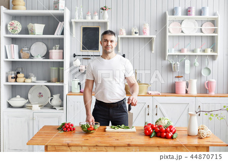 Portrait of handsome smiling man chopping vegetables in the kitchen. The concept of eco-friendly Portrait of handsome smiling man chopping vegetables in the kitchen. The concept of eco-friendly 44870715