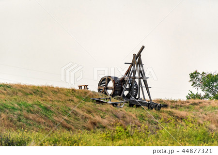 Old wooden catapult against grey sky background Old wooden catapult against grey sky background 44877321