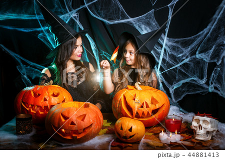 Happy Halloween . Beautiful caucasian mother and her daughter in witch costumes enjoy using magic Happy Halloween . Beautiful caucasian mother and her daughter in witch costumes enjoy using magic 44881413