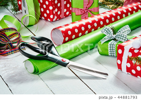 colorful papers for wrapping Christmas gifts and scissors on a white wooden table 44881793