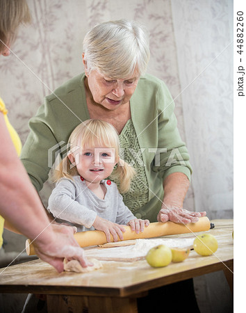 An old lady making little pies with a little girl. Girl looking in the camera An old lady making little pies with a little girl. Girl looking in the camera 44882260