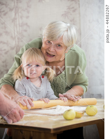 An old lady making little pies with a little girl. Looking in the camera An old lady making little pies with a little girl. Looking in the camera 44882267
