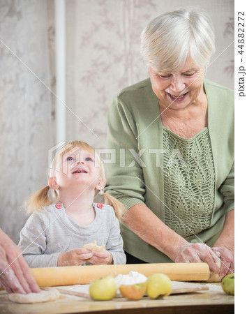 An old lady making little pies with a happy little girl. The girl looking up 44882272