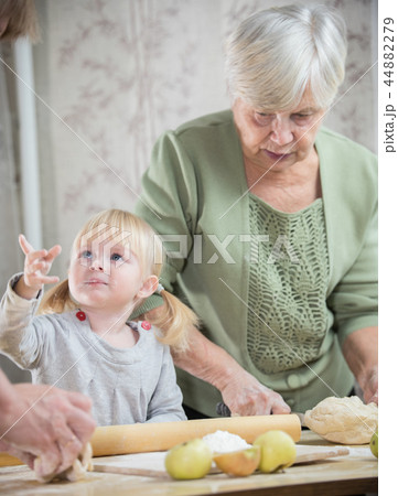 An old lady making little pies with a blonde little girl An old lady making little pies with a blonde little girl 44882279