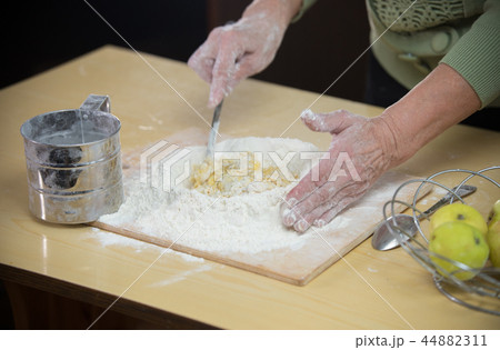 An old lady making little pies with apple pieces An old lady making little pies with apple pieces 44882311