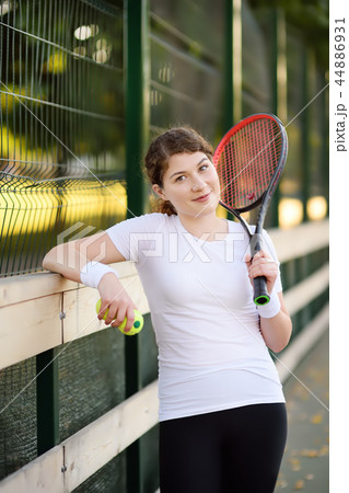 Young female tennis player with tennis ball and racket preparing to serve 44886931