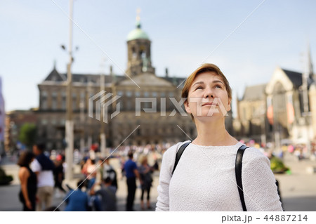 Mature woman standing on a Sunny autumn day in the Central dam square in the old city of Amsterdam. 44887214