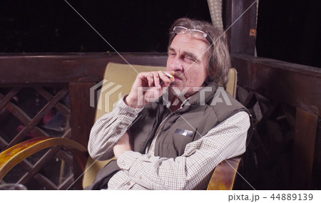 Senior man sitting in a chair and smoking Senior man sitting in a chair and smoking 44889139