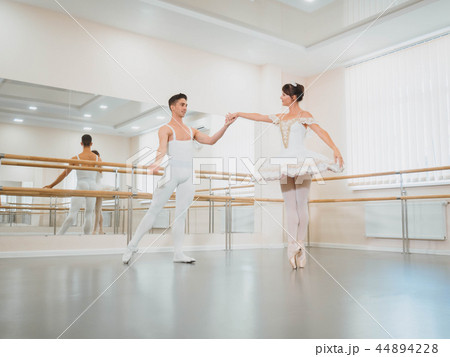 Training before performance. Man dancing classical ballet, he rotating pretty woman in white tutu 44894228