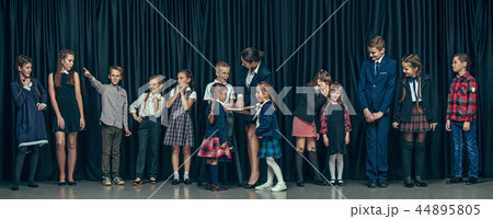 Cute stylish children on dark studio background. The beautiful teen girls and boy standing together Cute stylish children on dark studio background. The beautiful teen girls and boy standing together 44895805