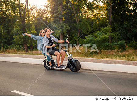 Lovely young couple driving electric bike during summer Lovely young couple driving electric bike during summer 44896215
