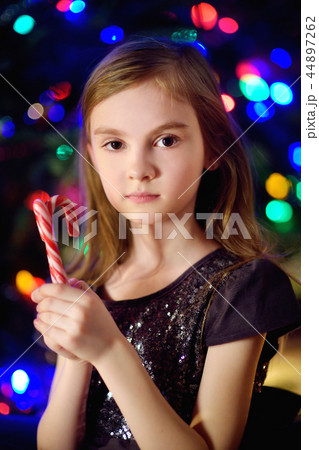 Christmas portrait of happy little girl by a fireplace in a cozy dark living room Christmas portrait of happy little girl by a fireplace in a cozy dark living room 44897262