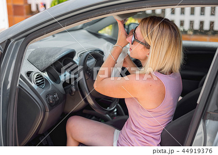 Young woman cleaning car interior  44919376