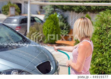 Young woman washing car with hose. Car detailing. 44919377