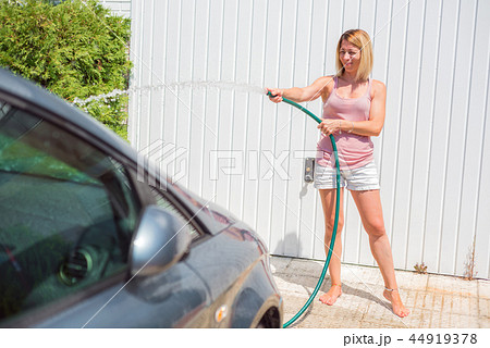 Young woman washing car with hose. Car detailing. 44919378