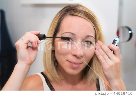 Beautiful woman applying mascara on her eyelashes 44919410