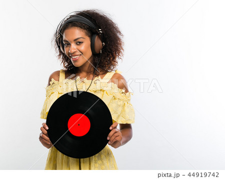 Young beautiful african american woman with headphones in yellow dress enjoying and dancing with Young beautiful african american woman with headphones in yellow dress enjoying and dancing with 44919742