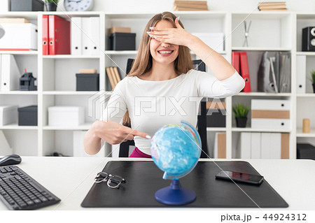 A young girl sitting in the office and in front of her on the table is a globe. A young girl sitting in the office and in front of her on the table is a globe. 44924312