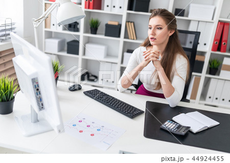 A young girl sitting at a computer Desk and working with documents. A young girl sitting at a computer Desk and working with documents. 44924455