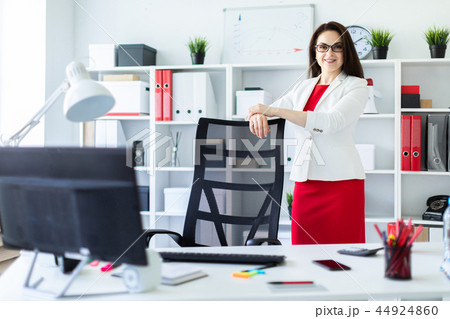 A young girl stands in the office near a chair in a high back. A young girl stands in the office near a chair in a high back. 44924860