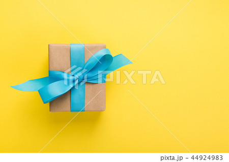 gift wrapped and decorated with blue bow on yellow gift wrapped and decorated with blue bow on yellow 44924983