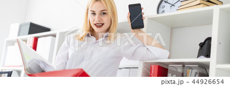 A young girl standing in the office and holding a folder. 44926654