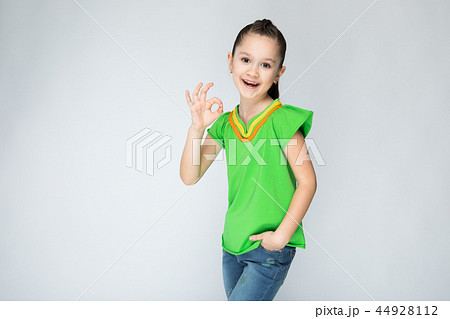Girl on a gray background shows the sign OK. Girl on a gray background shows the sign OK. 44928112